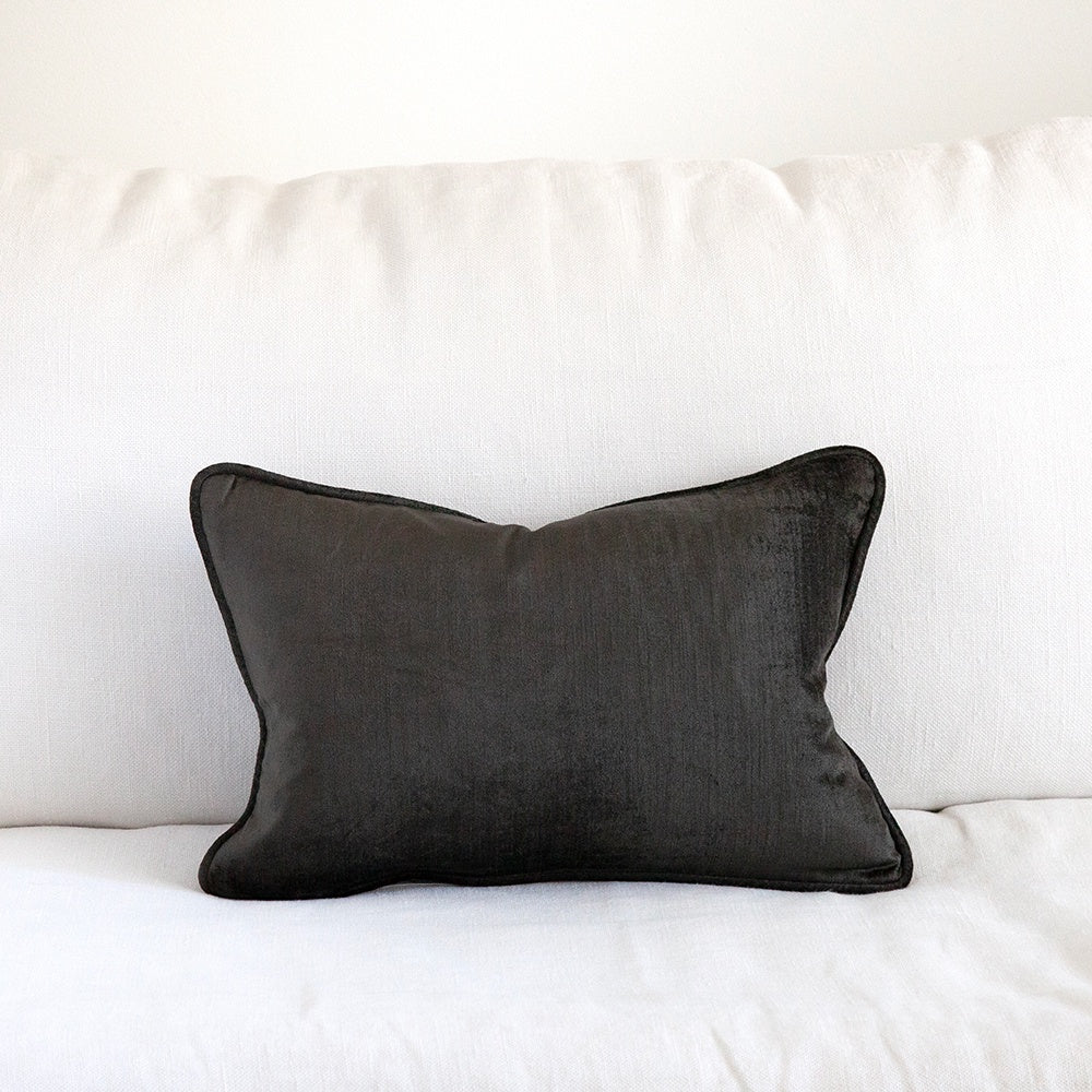 Small black velvet cushion on white sofa.