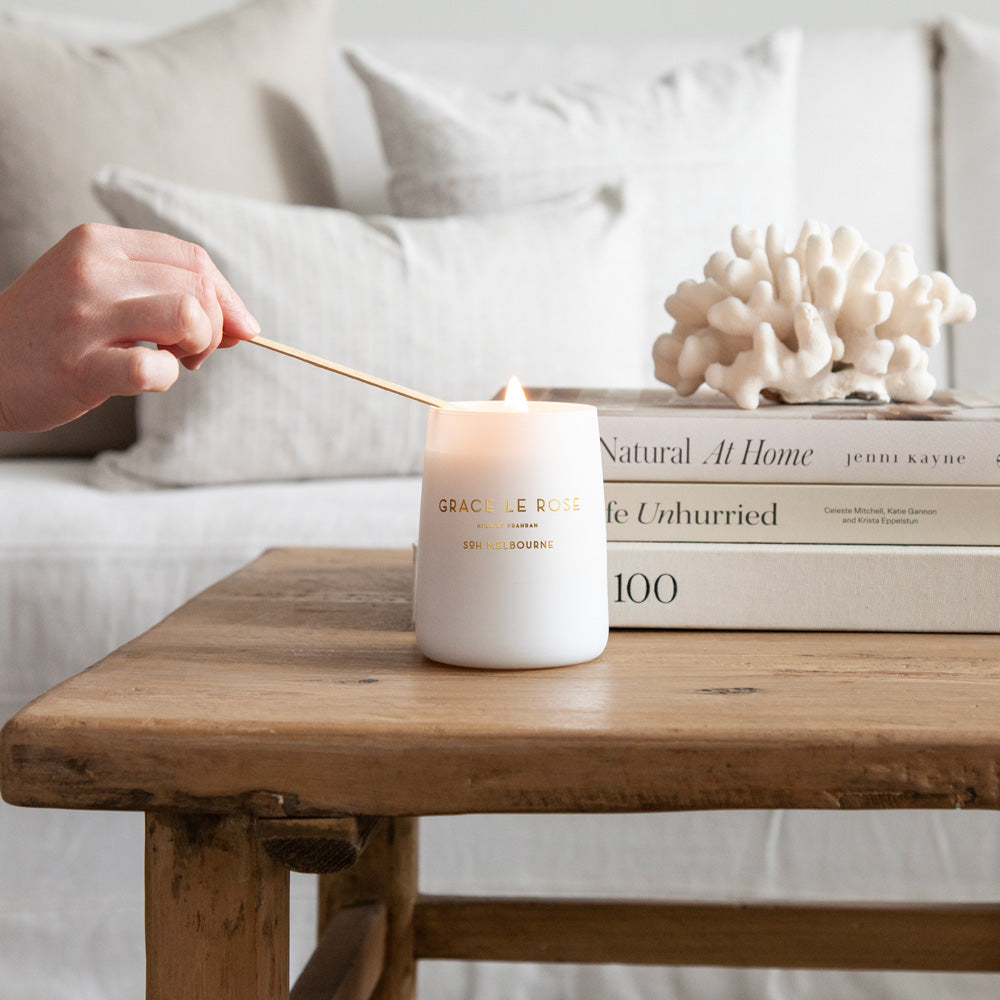Grace Le Rose candle on wooden coffee table.
