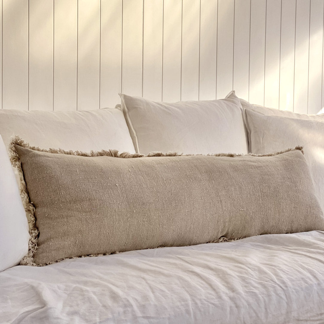 Natural linen long cushion with frayed edge on white sofa.