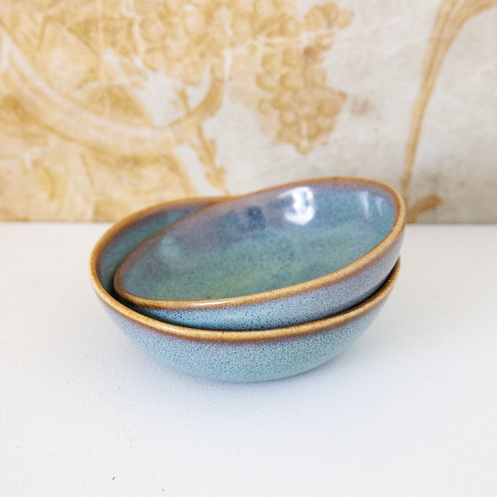 Small ceramic bowl with turquoise glaze and brown rim.