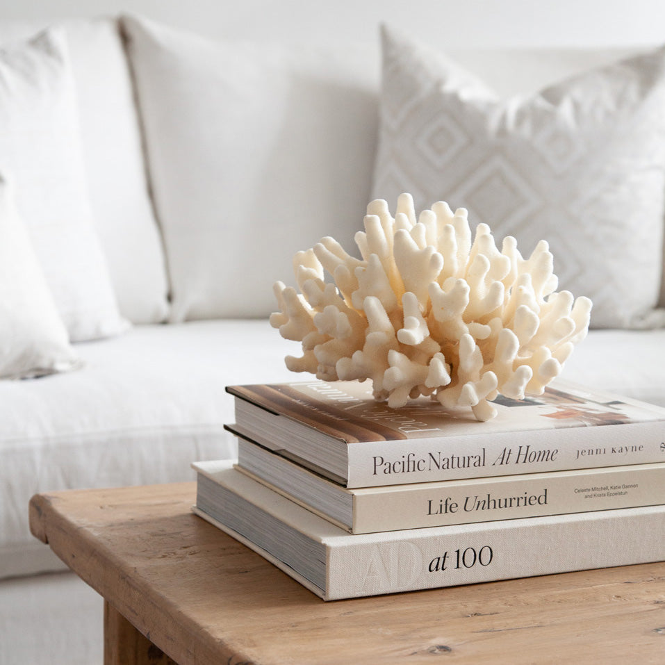 Pacific Natural At Home book styled on a wooden coffee table with coral in living room.