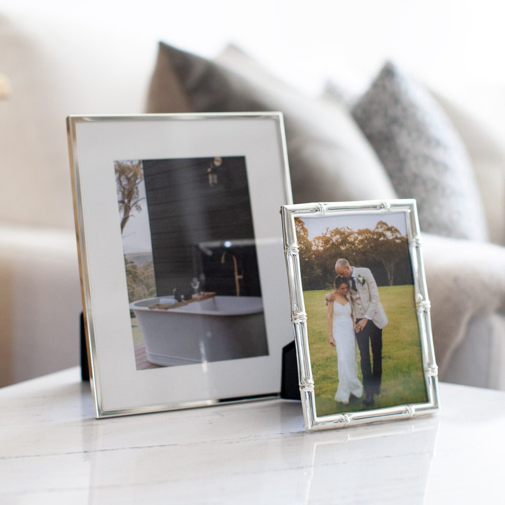 Two silver photo frames sitting together on a side table.