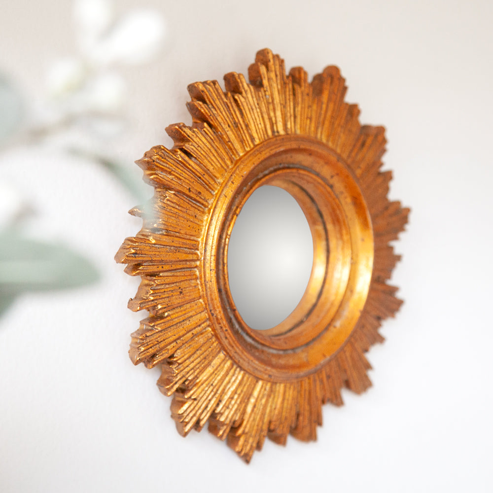 Small convex mirror with gold sunburst style frame.