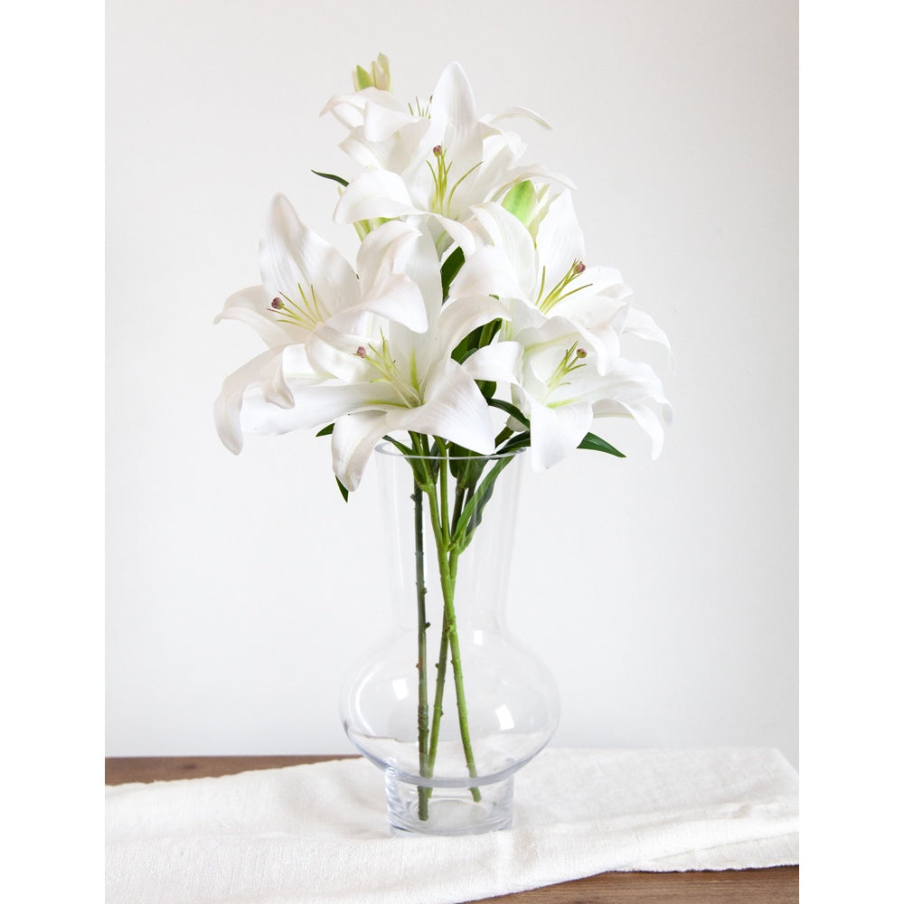 White lilies in clear glass vase.